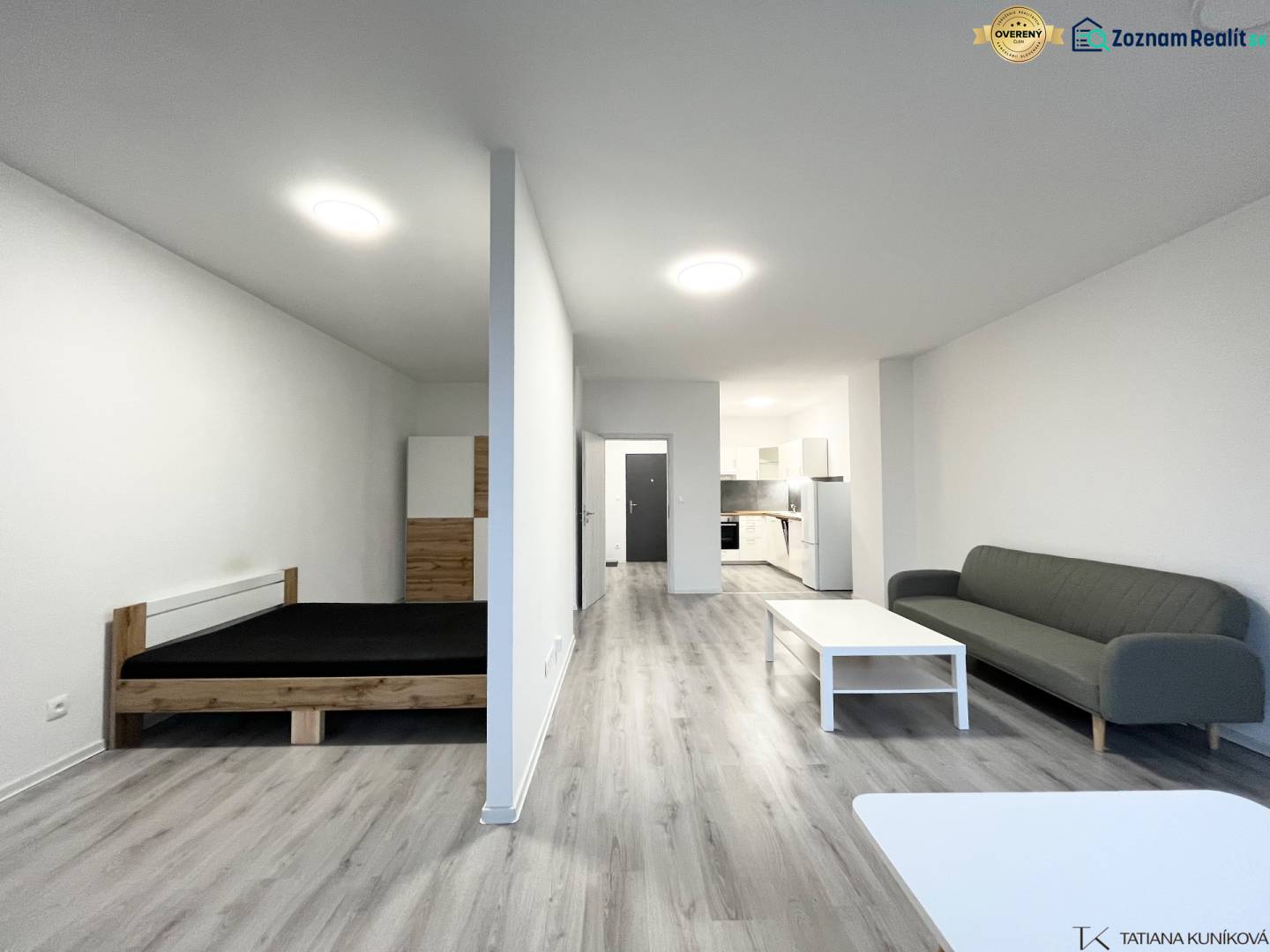 Interior of a 1-room apartment with a wooden decor floor, bed, and sofa.