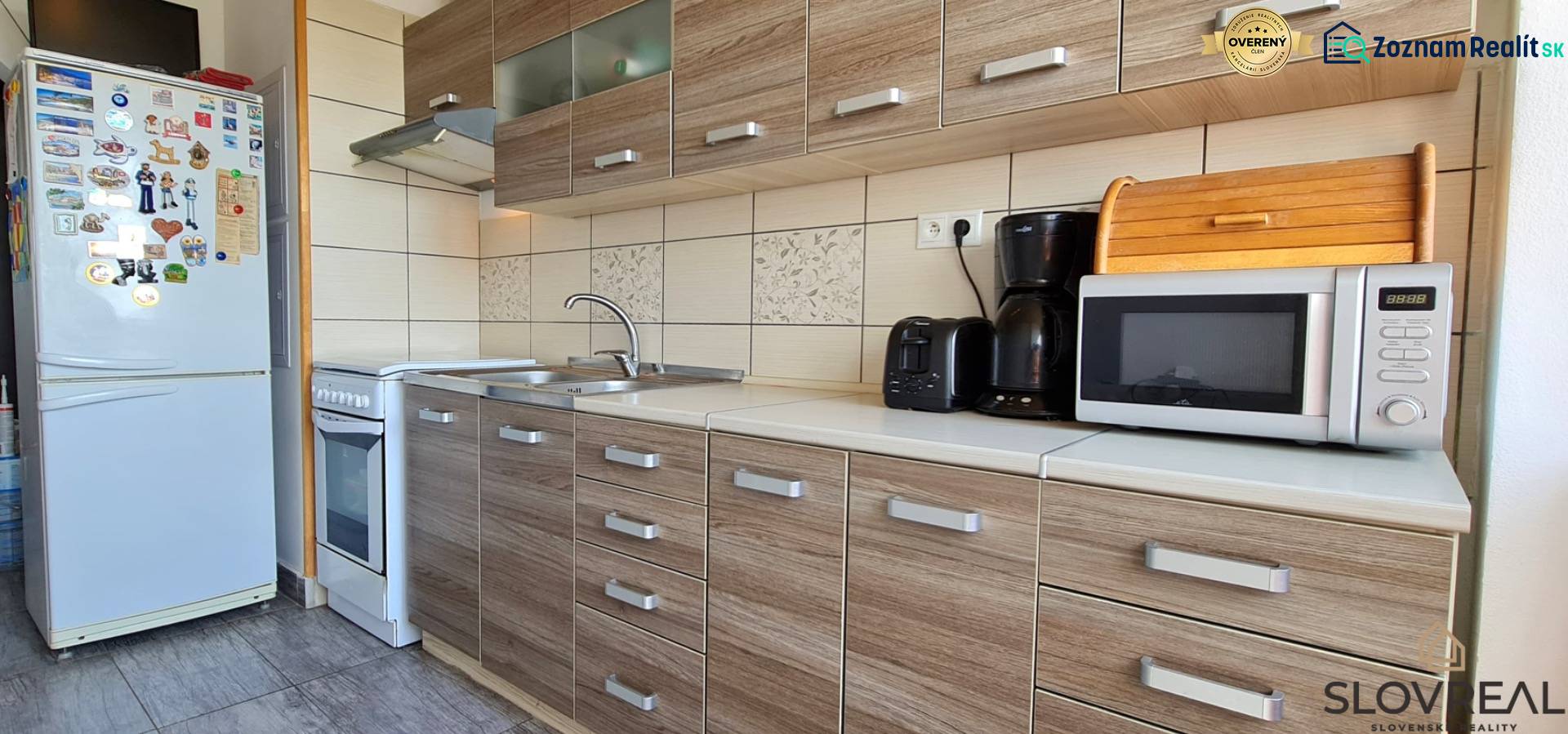 A kitchen in a 2-room apartment with a wooden decor floor and appliances.