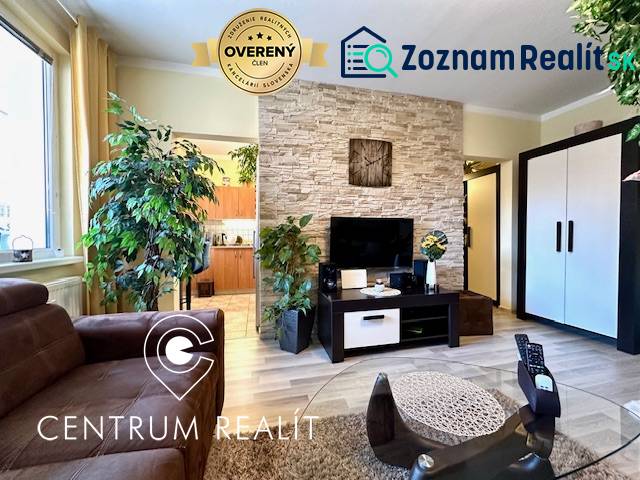 A living room in a studio apartment with plants and a wooden decor floor.