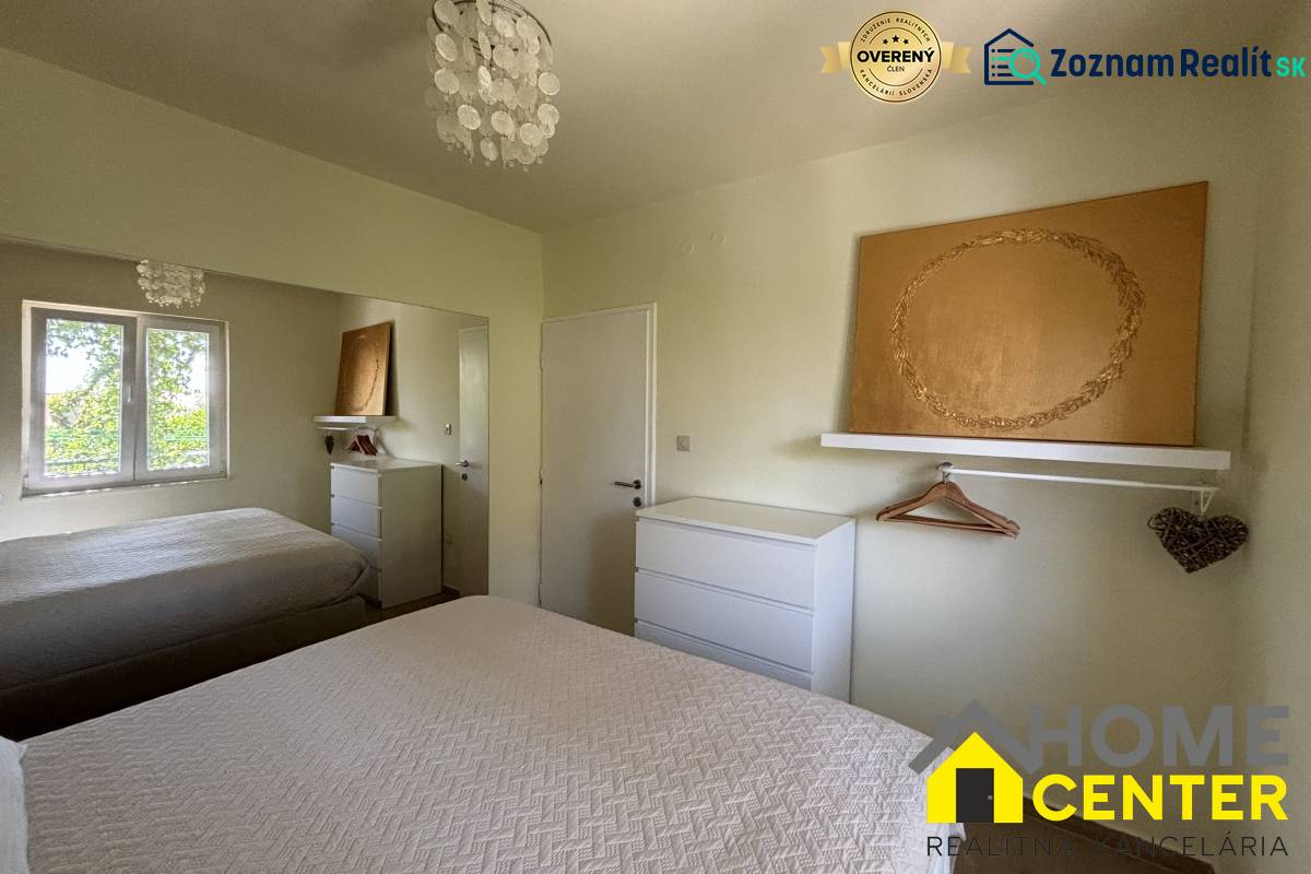 A bedroom in a family house with white furniture, a mirror, and textured bed covers.