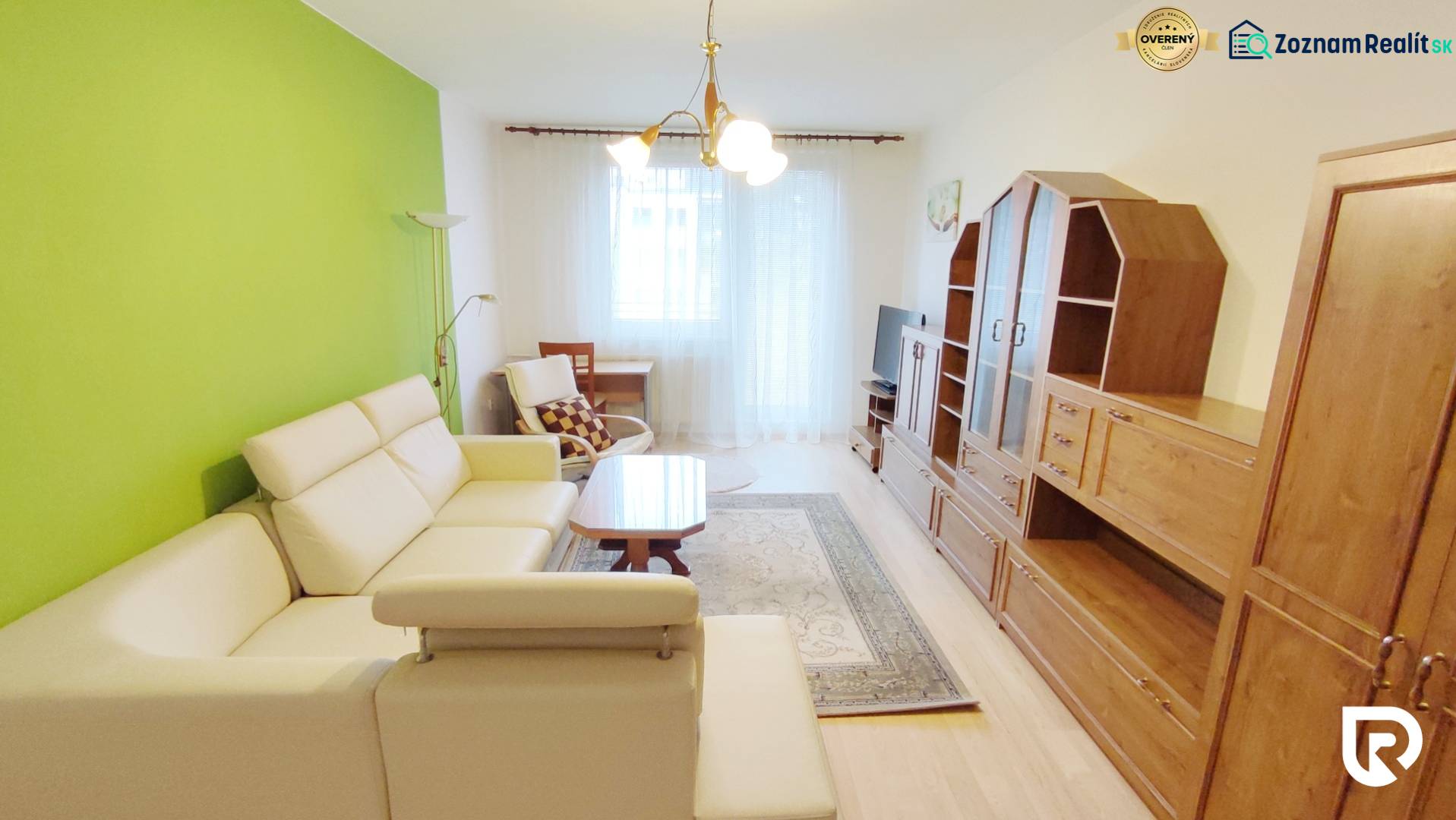 Living room in a 2-room apartment with a cream sofa, green wall, and set.