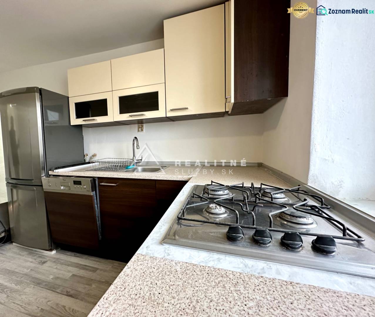 A kitchen in a 2-room apartment with a gas stove and a floor with a wood decor.