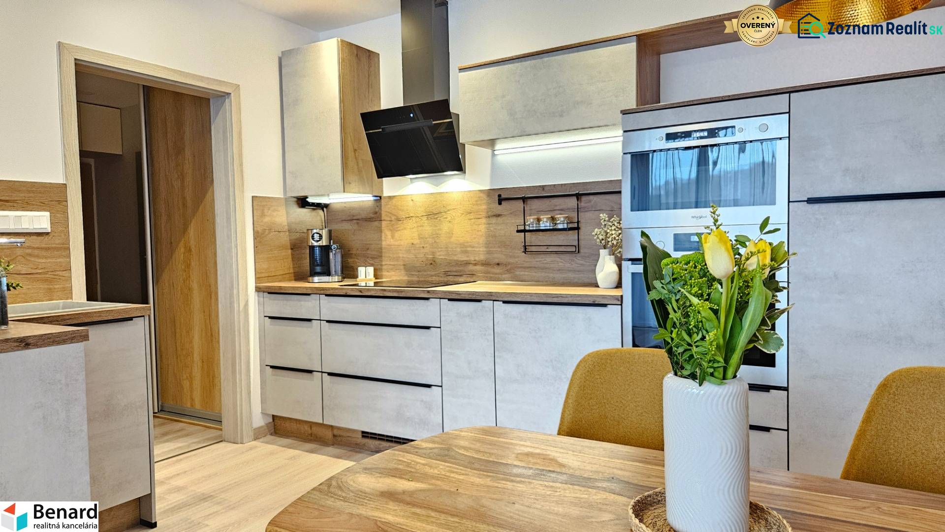 A kitchen in a studio apartment with wooden floor decor and modern equipment.