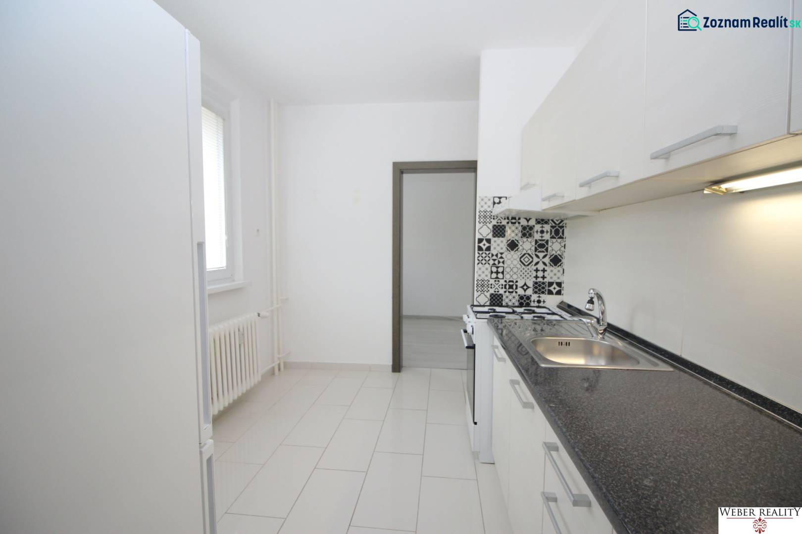 A kitchen in a 3-room apartment with tiled flooring, patterned tiles near the stove.