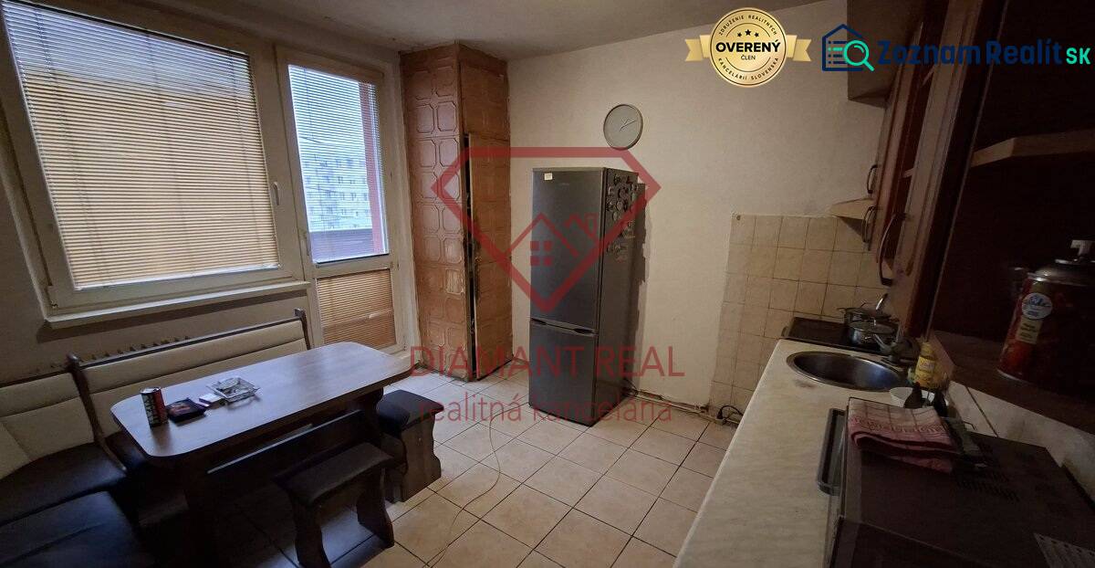 Kitchen in a 3-room apartment with a dining table and a refrigerator, tiled floor.