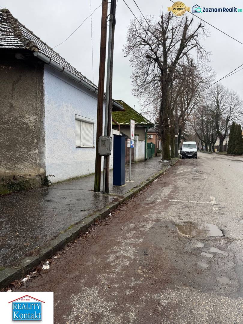 A family house on Komenského Street in Šurany, by the road with an electric pole and trees.