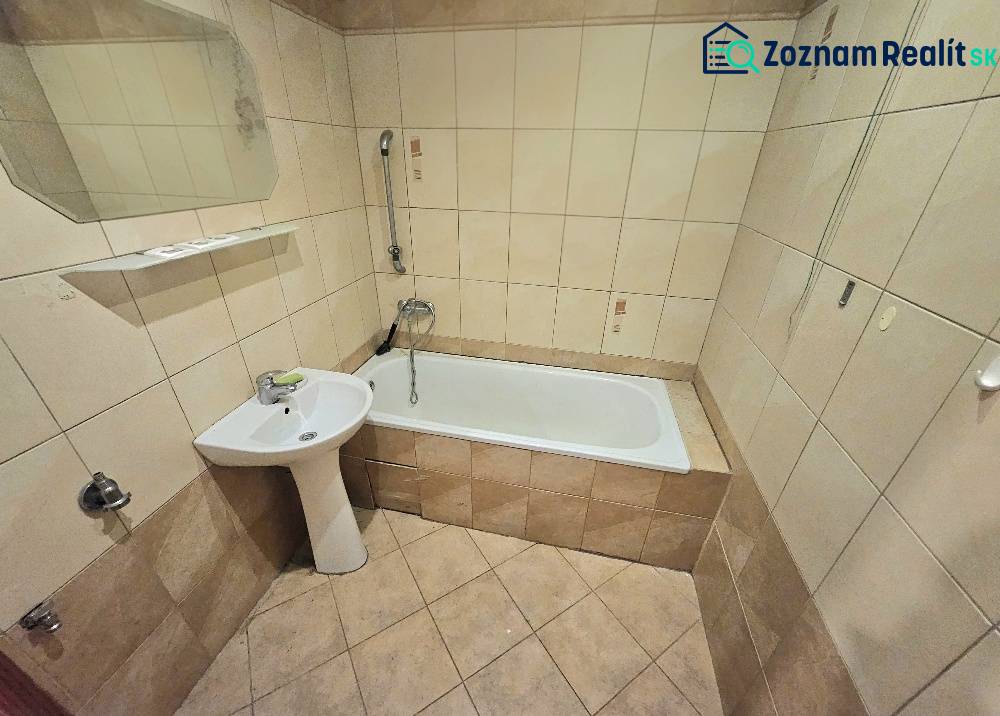 A bathroom in a 3-room apartment with a bathtub, a sink, and beige ceramic tiles.