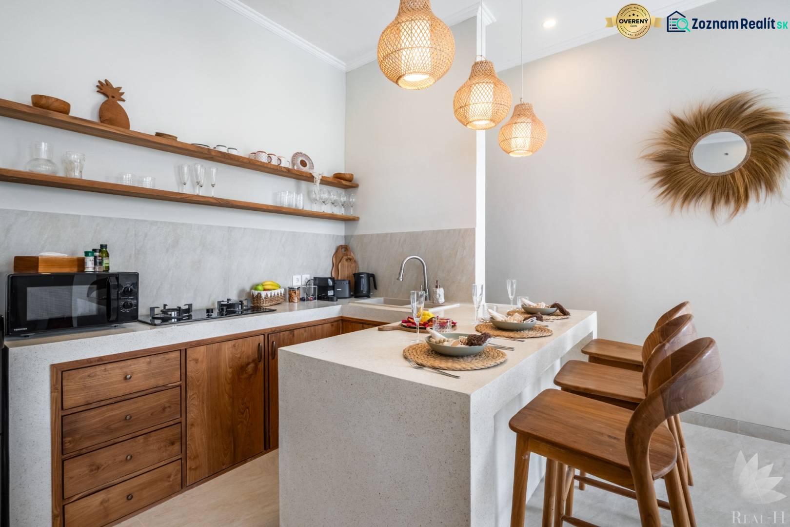 A villa kitchen with stylish wooden elements, bar stools, and pendant lamps.