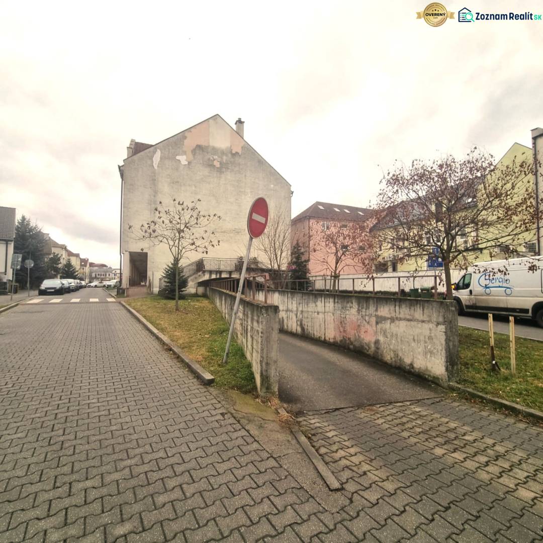 Malé námestie Street in Malacky, with garages in the foreground and a no entry sign.