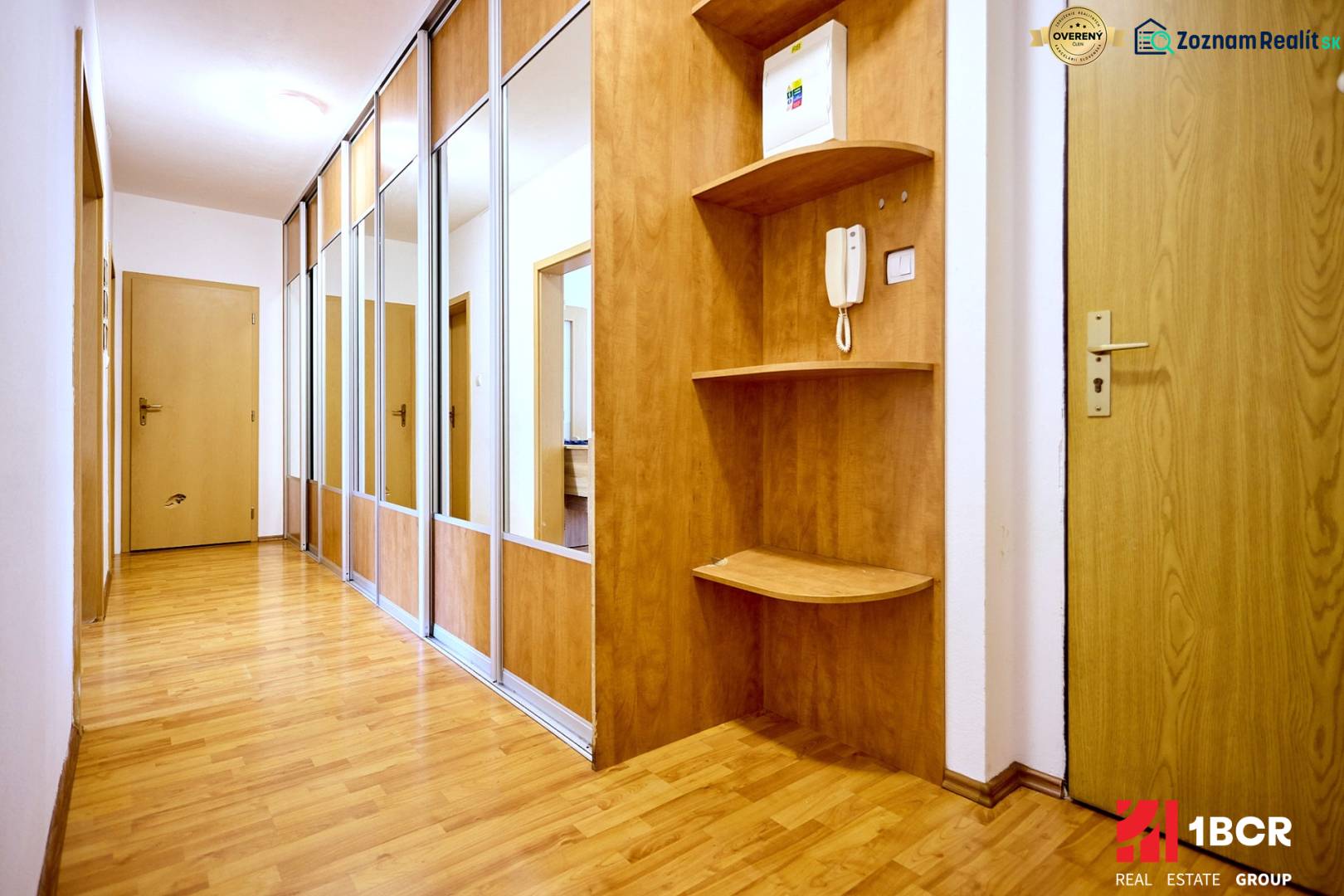 The hallway in a 2-room apartment with a wooden decor floor and built-in cabinets.