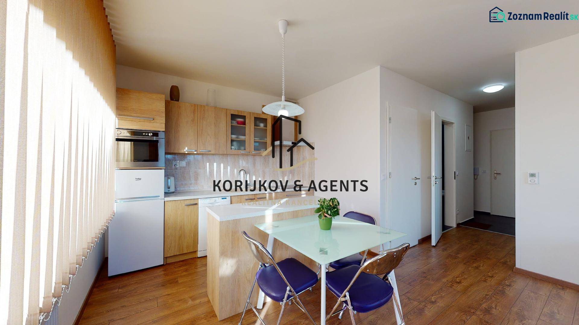 A kitchen in a 2-room apartment with a wood-patterned floor and a table with chairs.