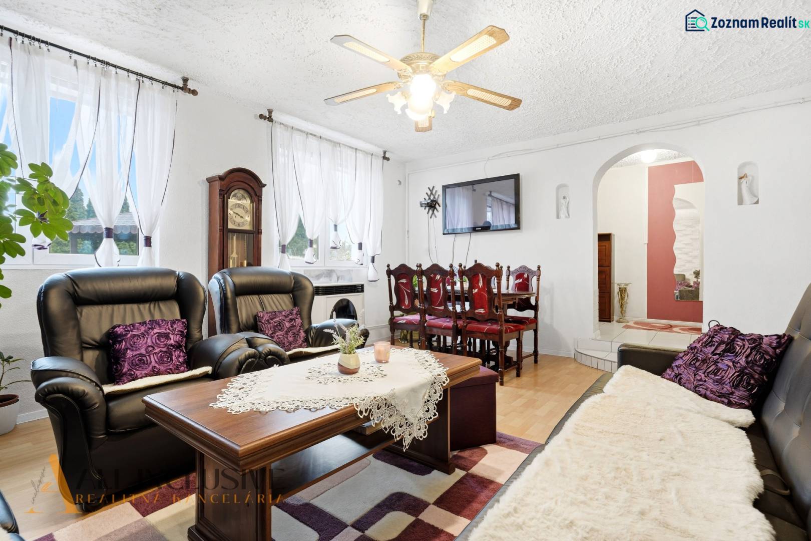 Living room of a family house with a fireplace, black sofas, and a floor with a wooden decor.