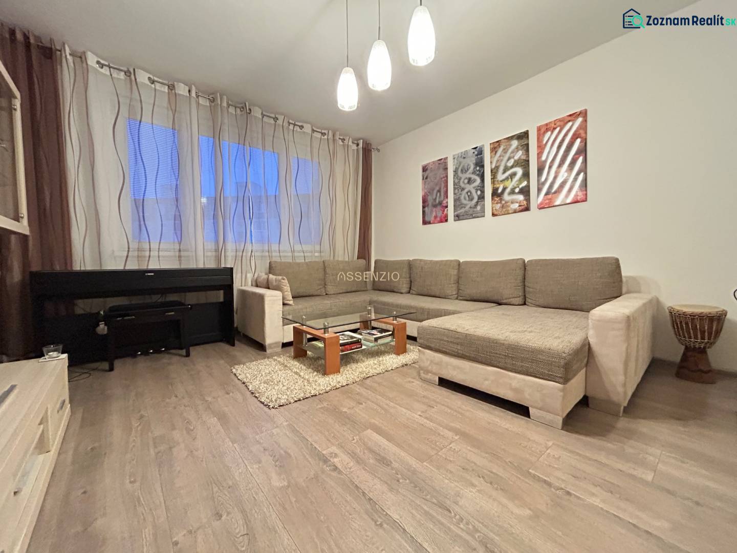 Living room in a 2-room apartment with a sofa, piano, and wooden decor flooring.