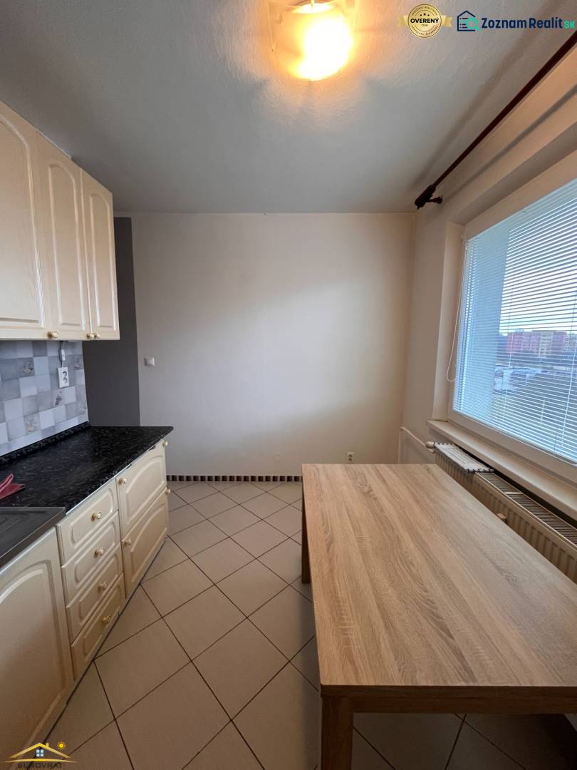 A kitchen in a 2-room apartment with ceramic tiles and a dining table.