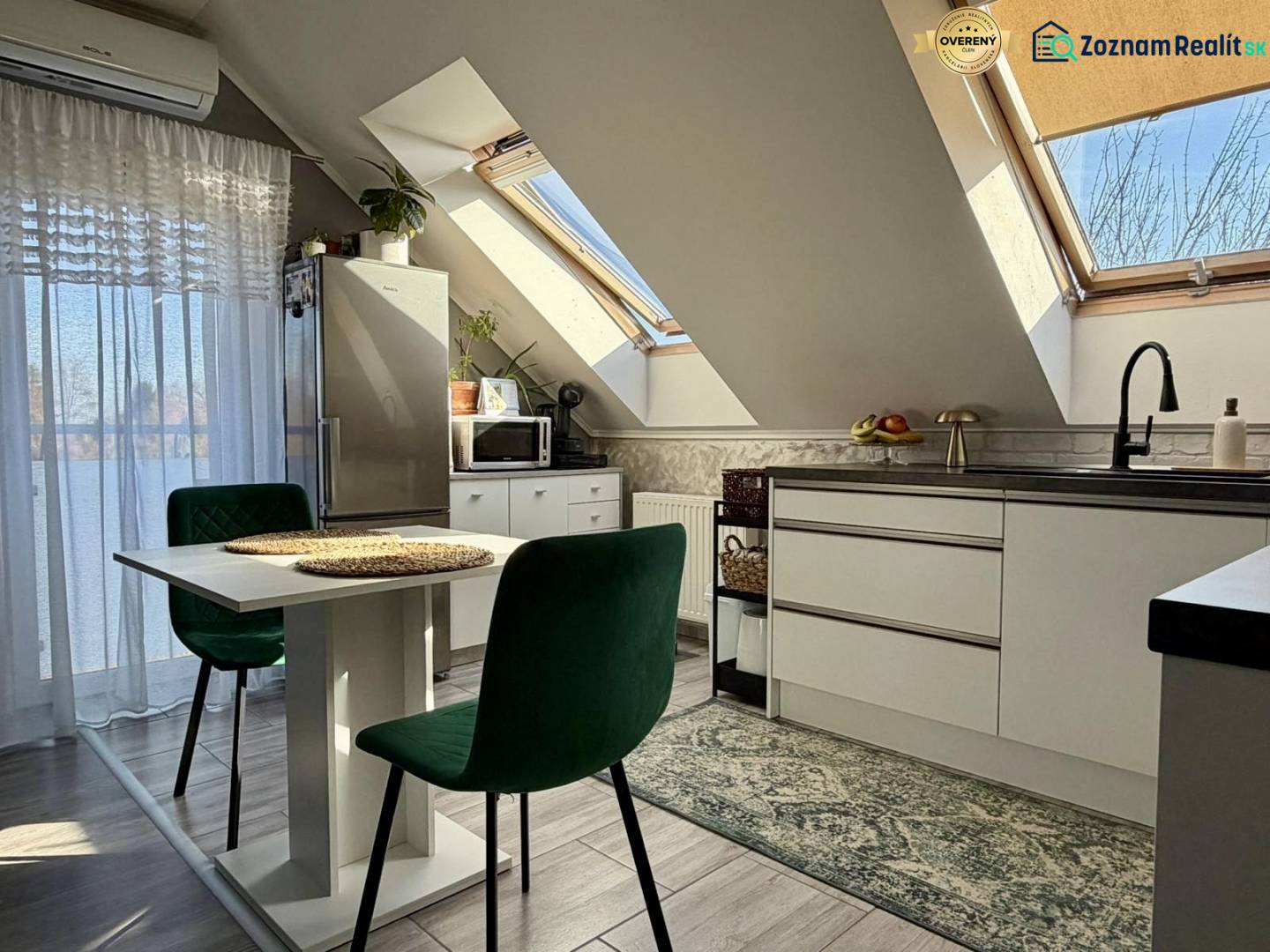 Kitchen in a 2-room apartment with slanted ceilings, skylights, and furniture.