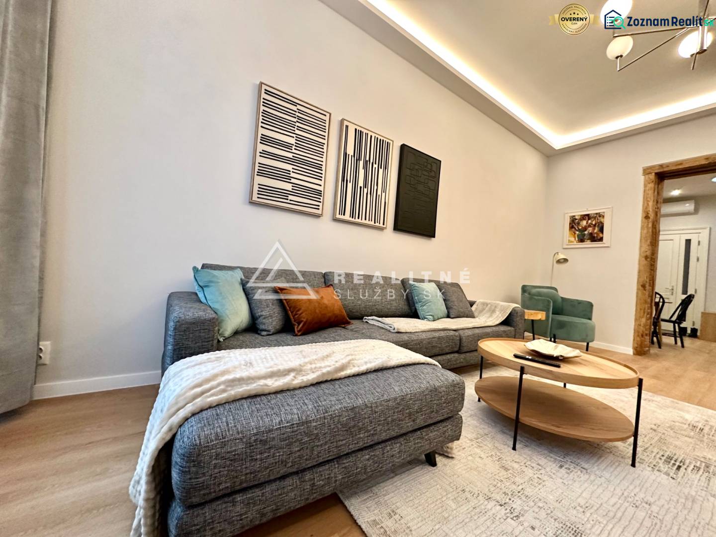 Living room with a sofa, wood-patterned flooring, and artworks in a 2-room apartment.