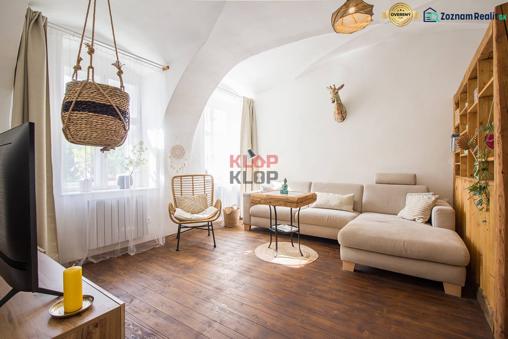 Living room in a studio apartment with a light sofa and a wooden decor floor.