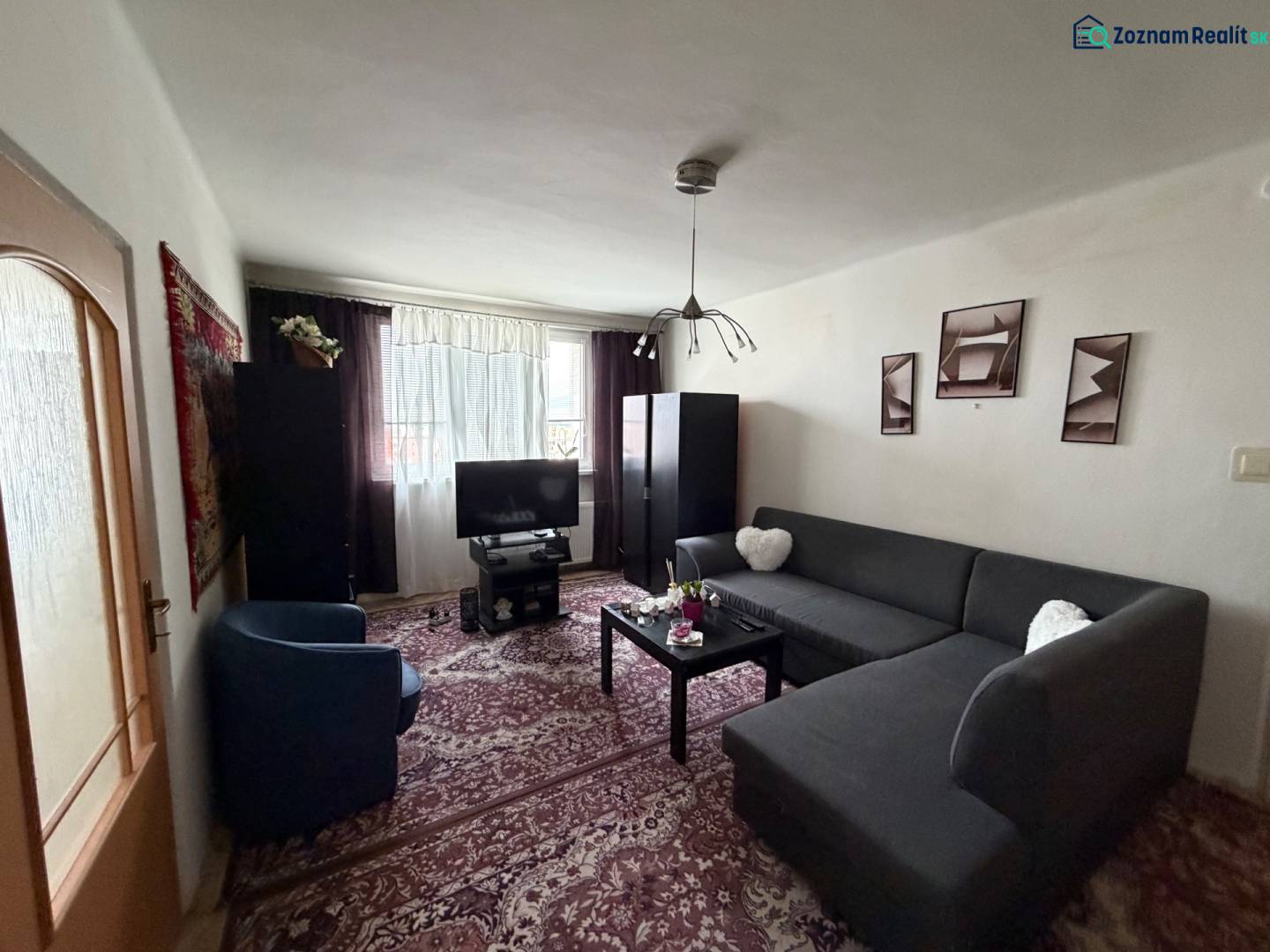 Living room with a corner sofa, carpet, and television in a 3-room apartment.