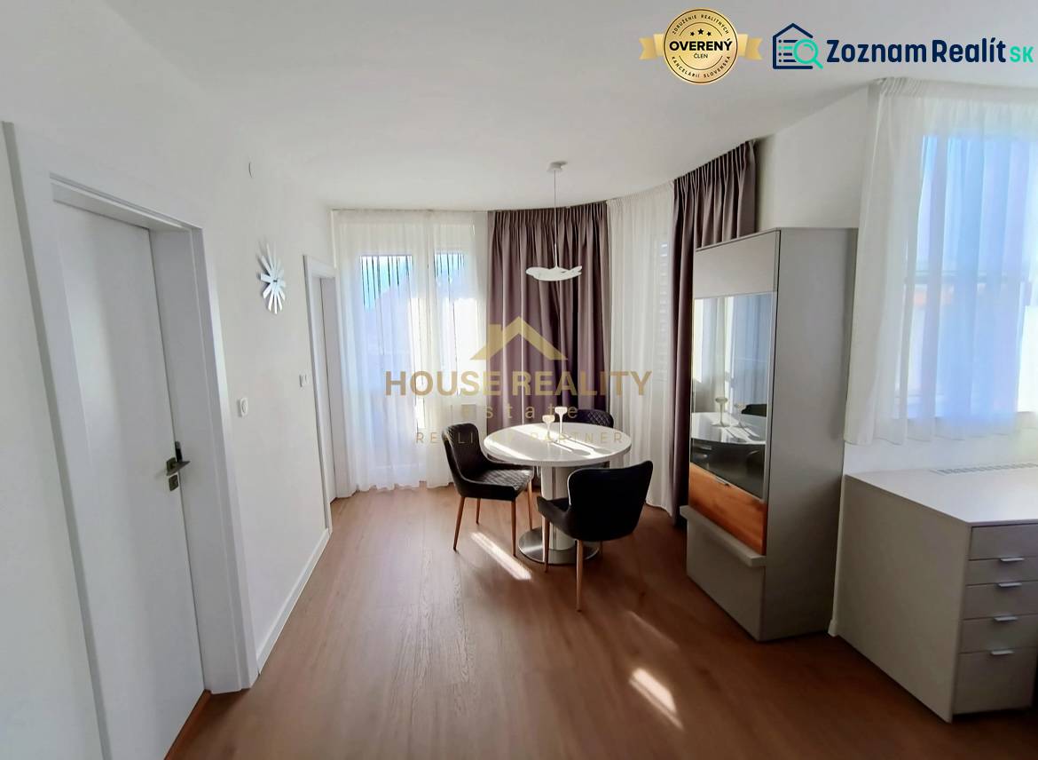 Dining area in a 2-room apartment with a round table and wooden decor flooring.