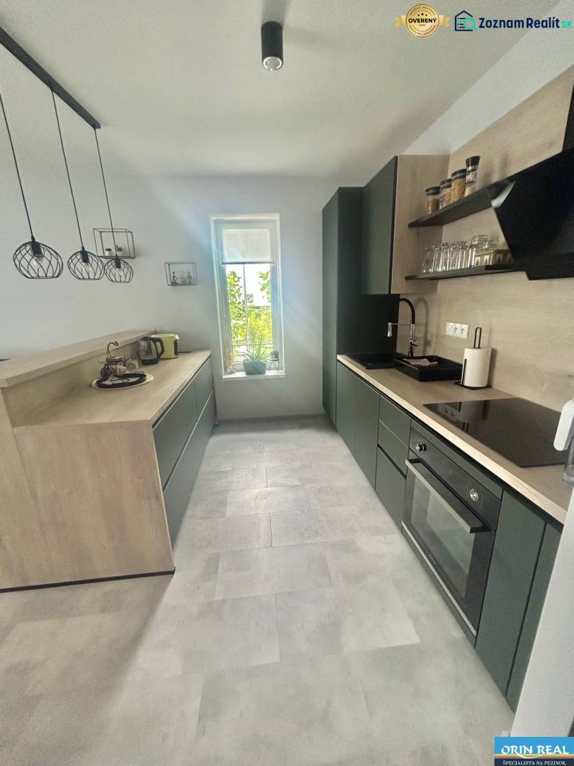 A kitchen in a two-room apartment with black cabinets and a gray floor.