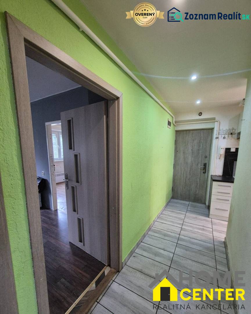 A hallway in a 3-room apartment with an entrance to a floor with a wooden decor and a green wall.