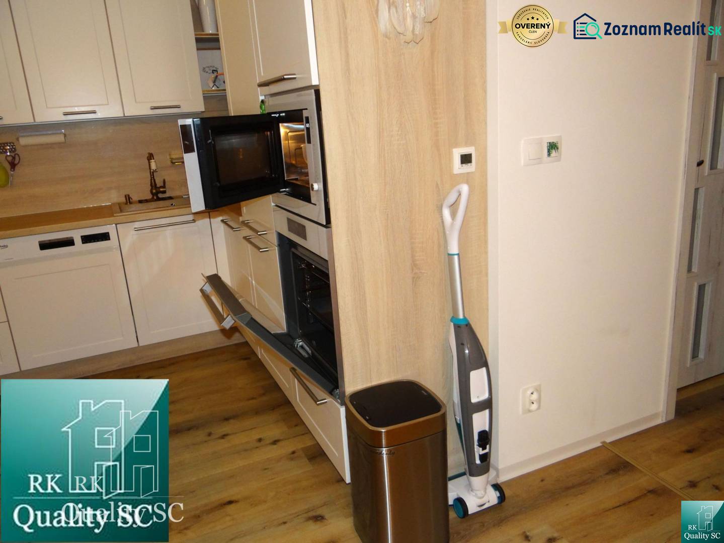 A kitchen in a 2-room apartment with a wooden decor floor and modern appliances.