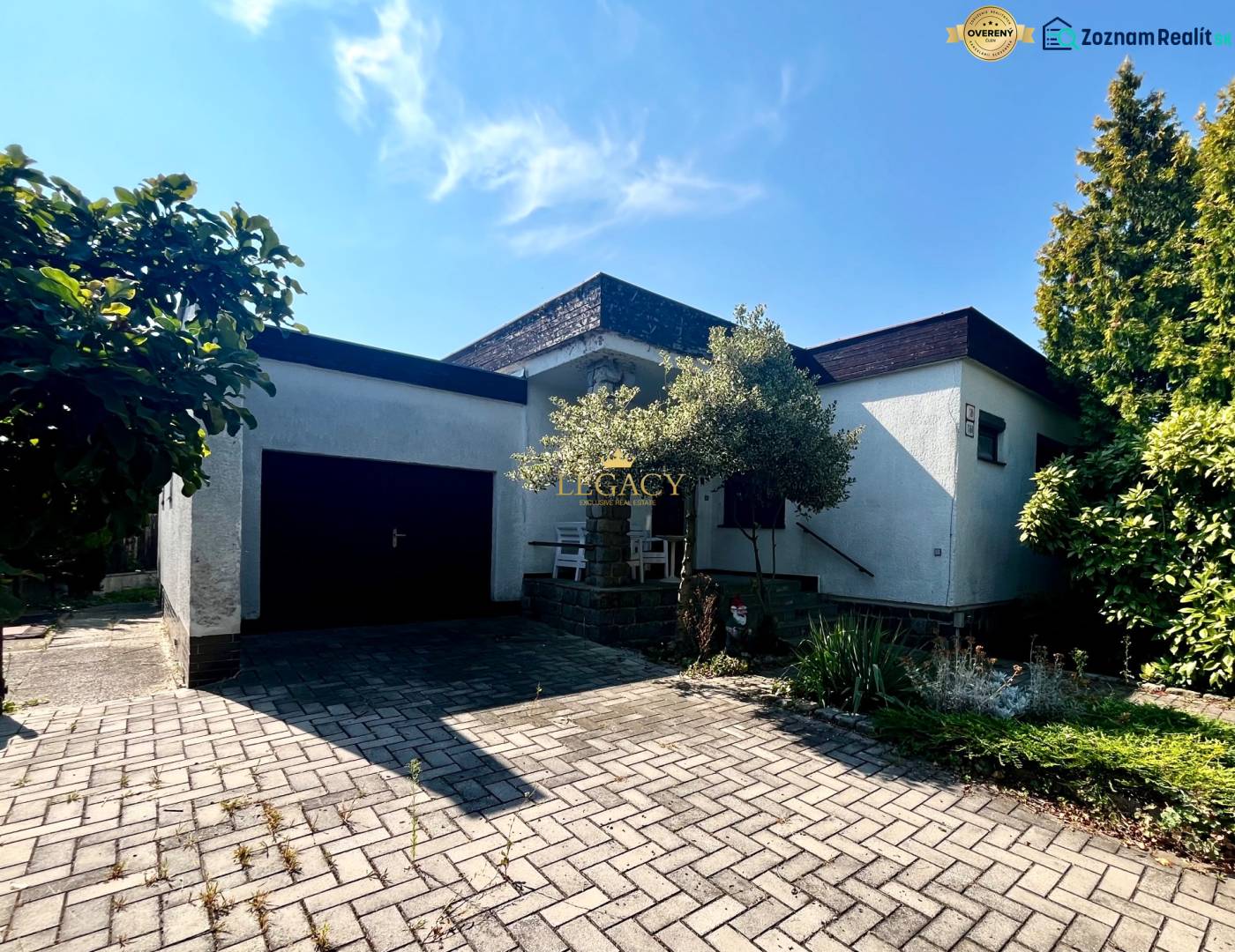A family house in Ivanka pri Dunaji with a garage and a flower bed, on a paved walkway.