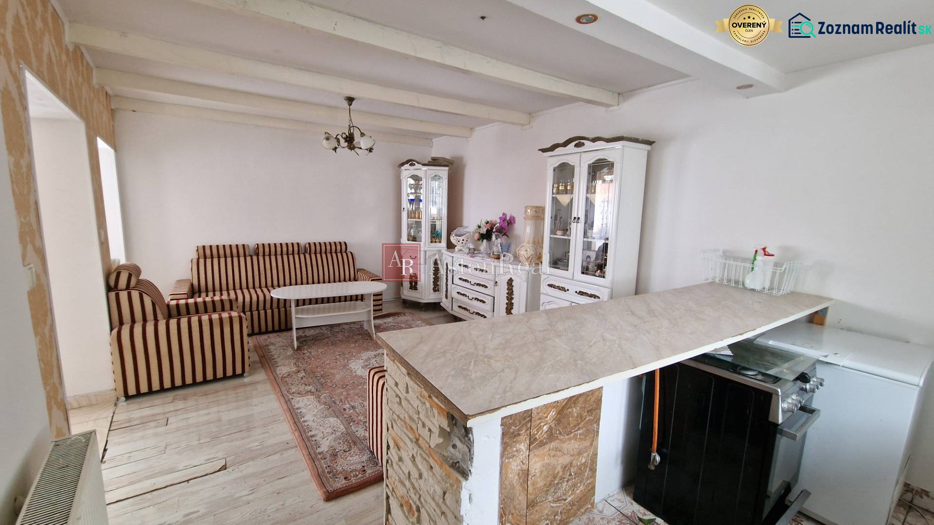 Living room in a family house with striped furniture, a decorative cabinet, and a wooden-patterned floor.