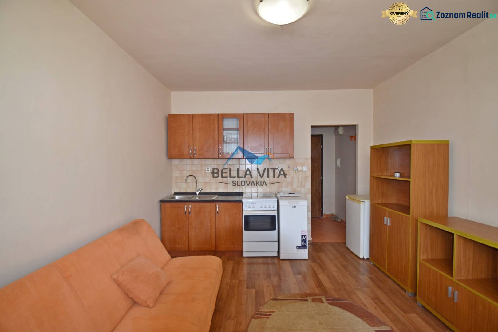 Studio apartment with a kitchenette, sofa, and furniture on a floor with a wooden decor.