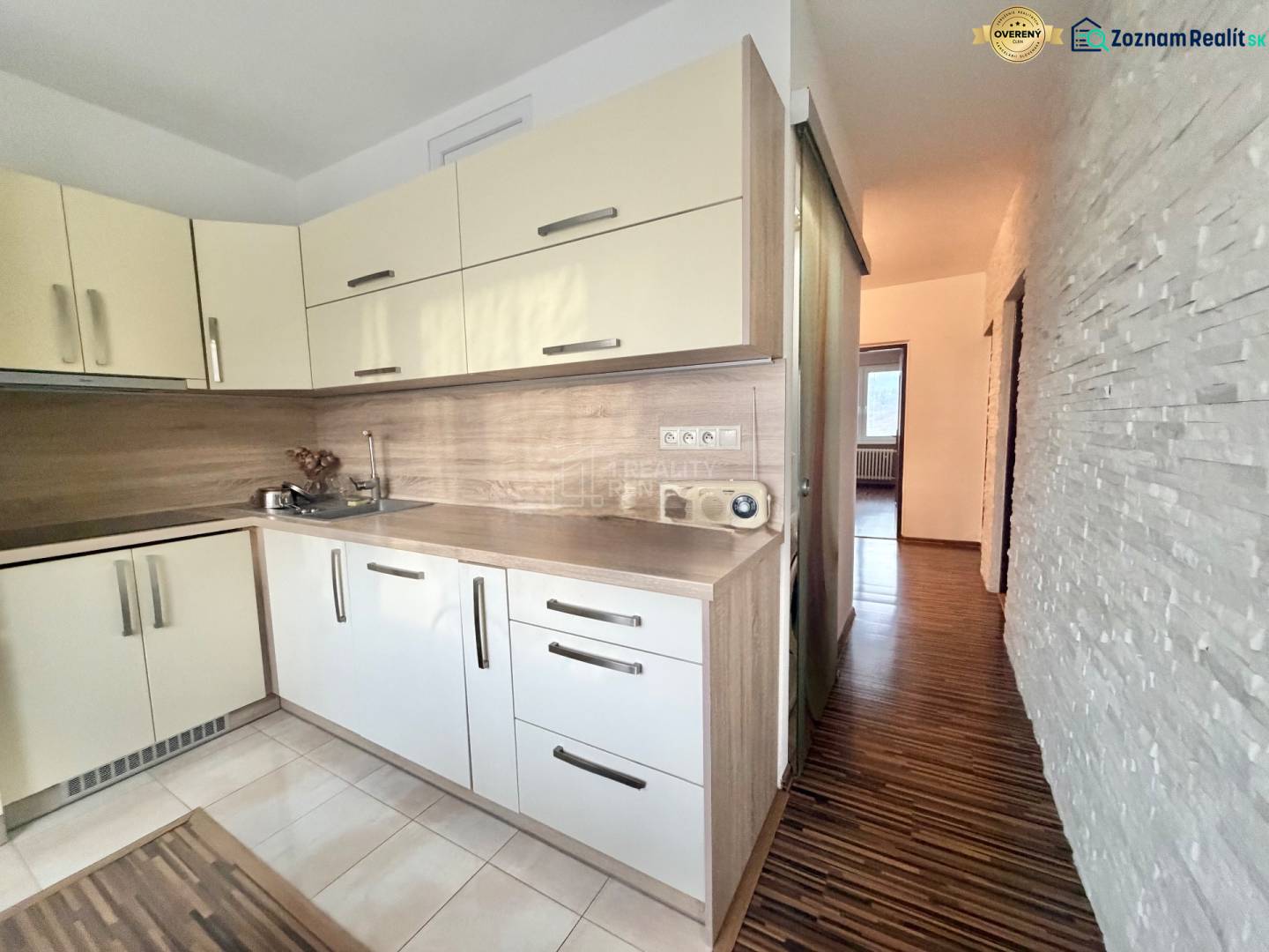 A kitchen in a 4-room apartment with a wooden decor floor and light cabinets.