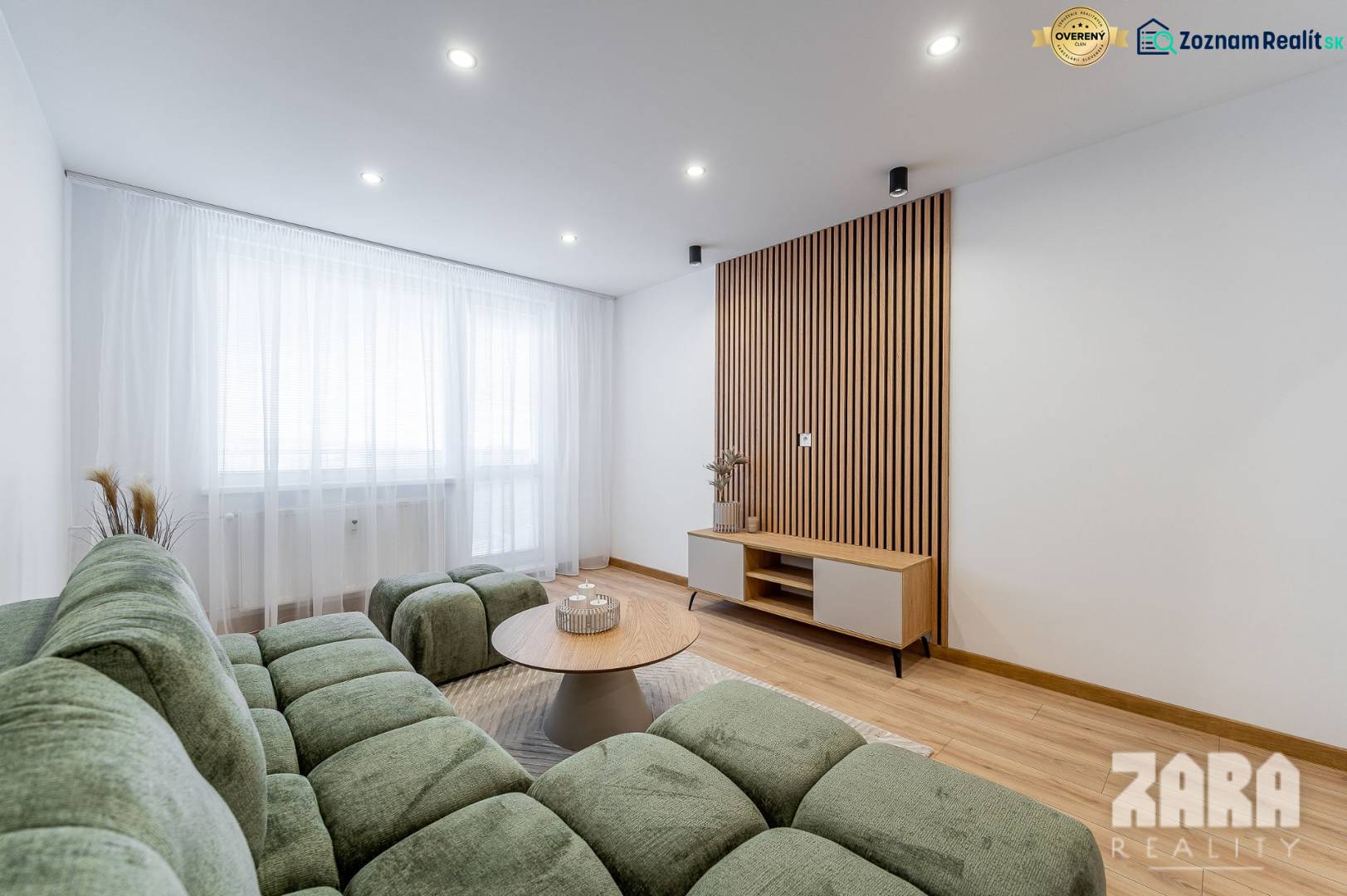 Living room with wood-patterned flooring, green sofa, and light-colored furniture in a two-room apartment.