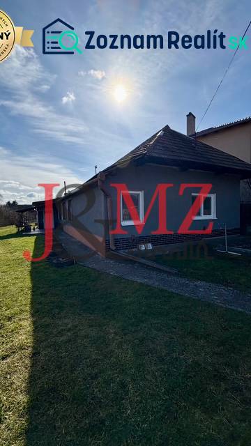 A family house in Mýtne Ludany, surrounded by a garden, with a blue sky and sunshine.