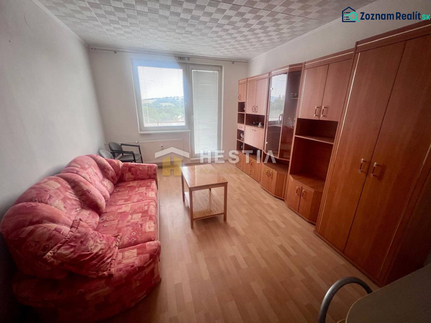 A room in a 3-room apartment with a sofa, cabinets, and a table on a light floor.