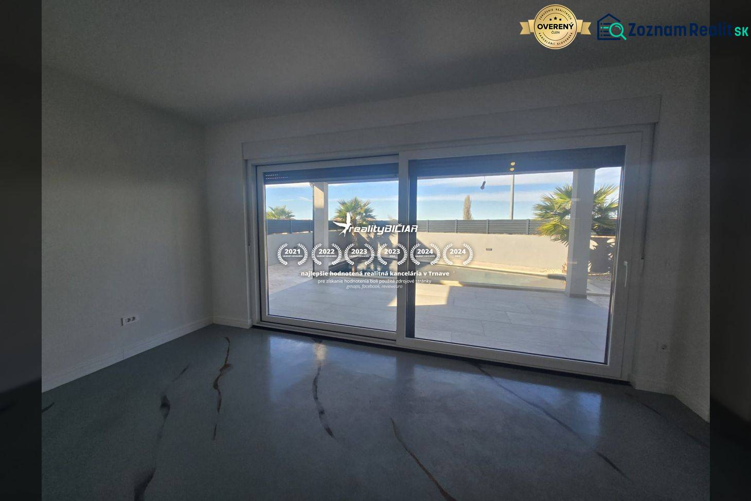 Interior of a villa with large glazing and a view of the exterior with a pool.