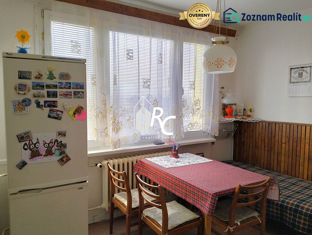 A kitchen in a 2-room apartment with a dining table, chairs, and a fridge with magnets.