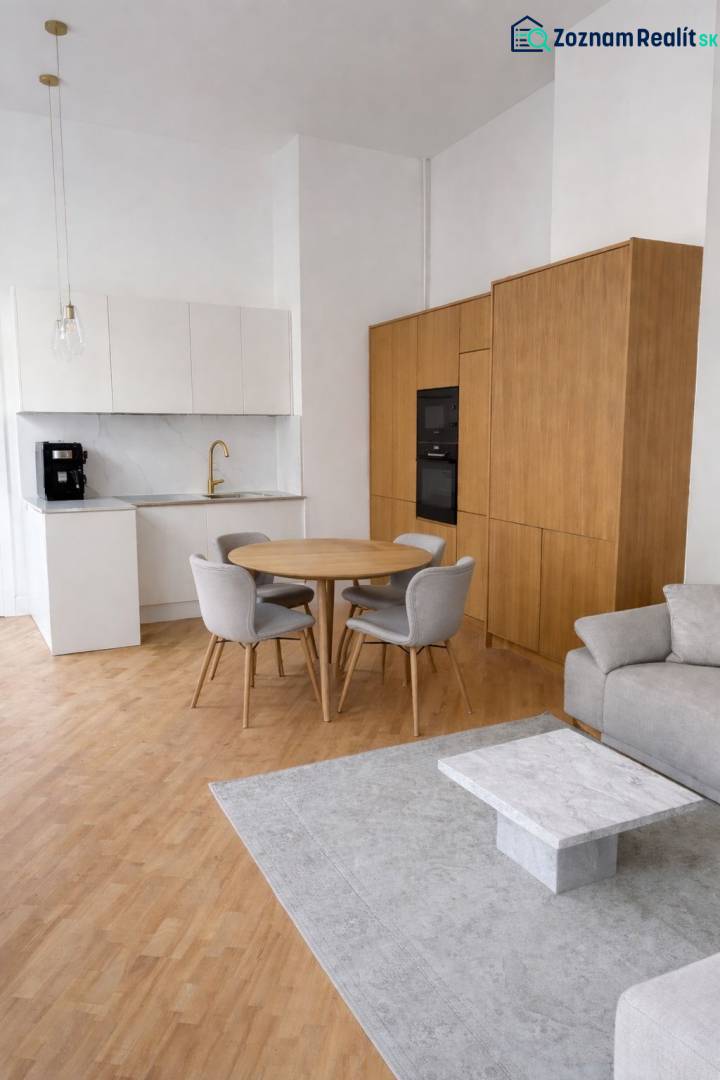 A kitchen in a 3-room apartment with a wood-patterned floor, a gray carpet, and a dining table.