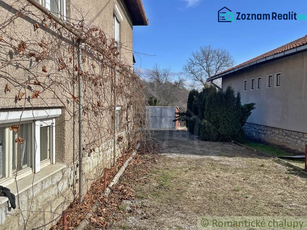 A family house in Bretka with an old facade, vine, and a yard with trees.