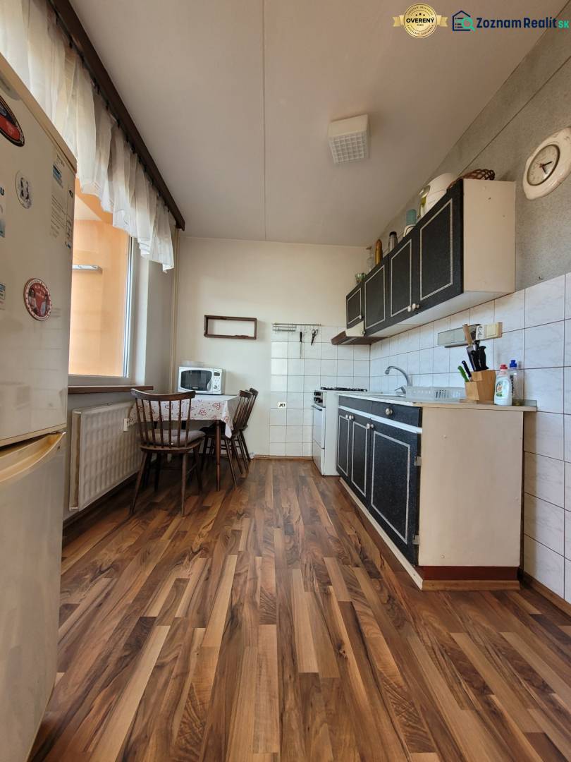 A kitchen in a 2-room apartment with a wooden decor floor and a dining table.