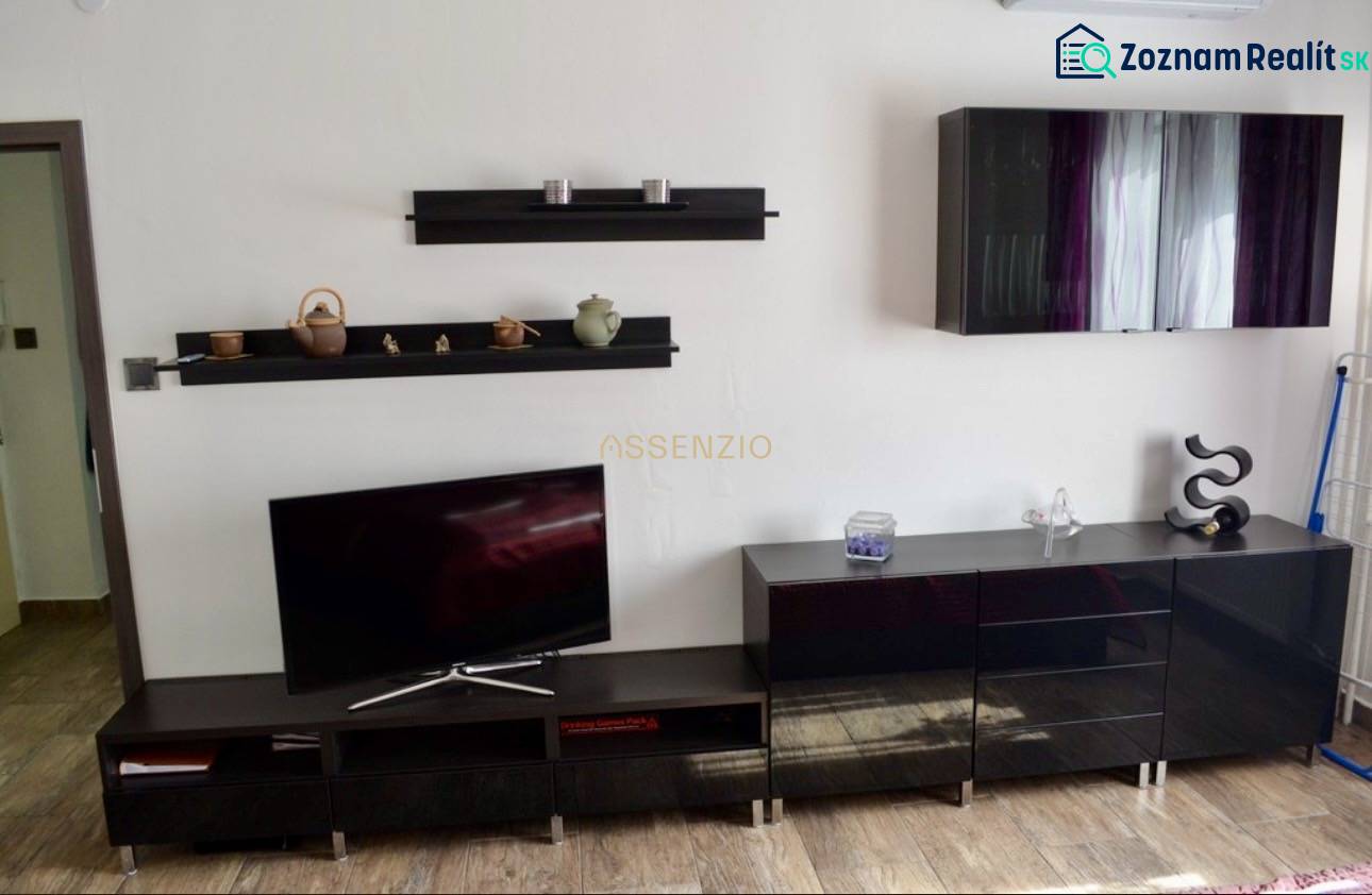 Interior of a 2-room apartment with dark furniture and a television on a wooden floor.