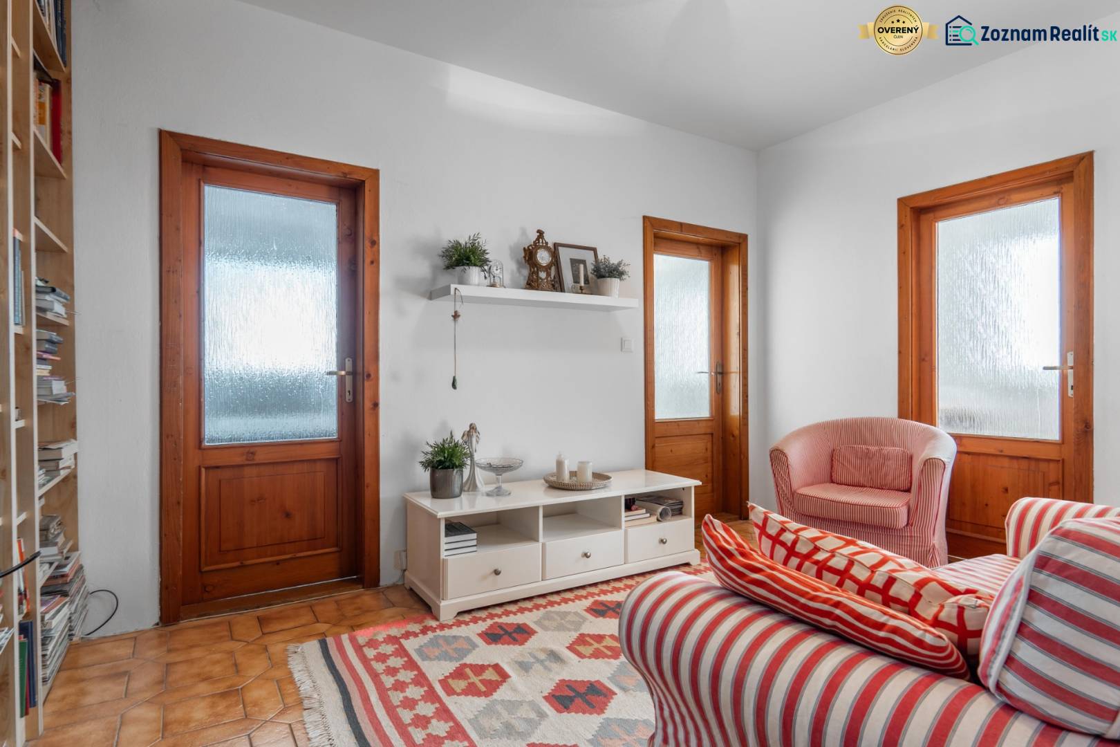 Living room in a 4-room apartment with red striped armchairs and a shelf on the wall.