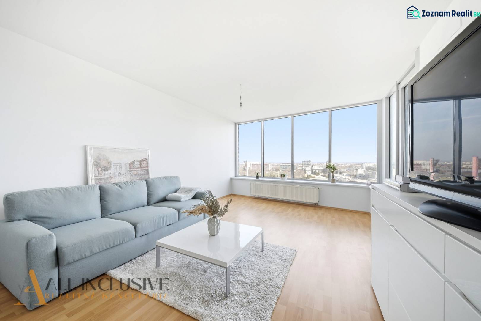 Living room with wood-patterned flooring, large windows, and a comfortable sofa in a two-room apartment.