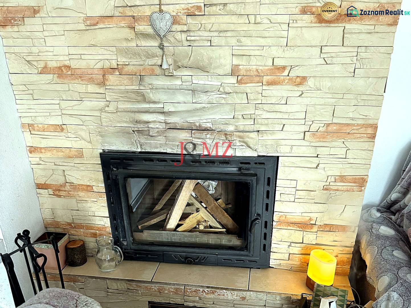 Fireplace in a 2-room apartment with artificial stone cladding and a decorative heart.