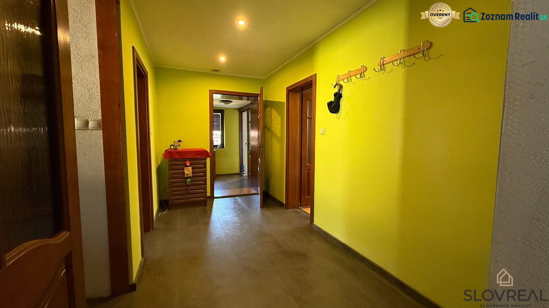 A hallway with coat racks and yellow walls, a floor with a wooden decor in a family house.