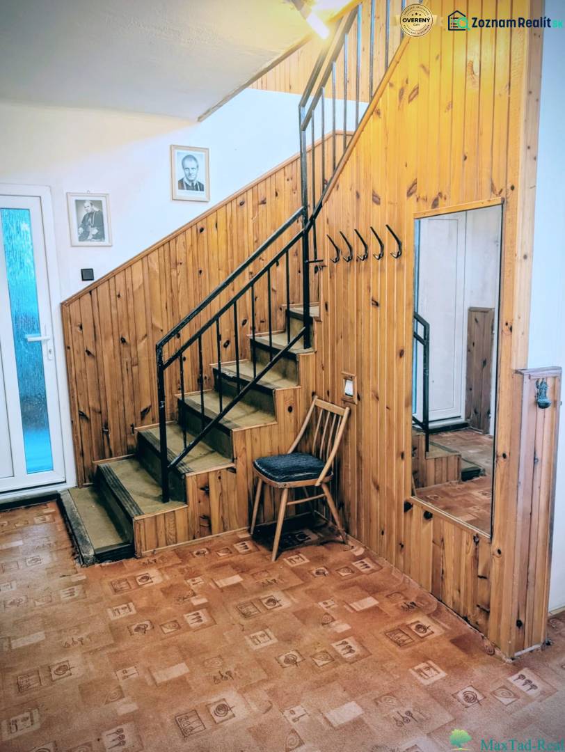 Interior of a family house with wooden paneling, a mirror, a staircase, and a floor with a wooden decor.