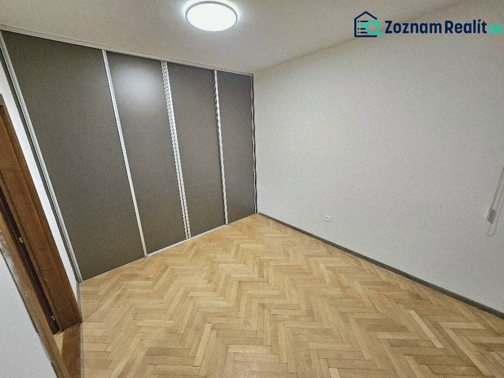A room in a 2-room apartment with a wooden decor floor and storage space.
