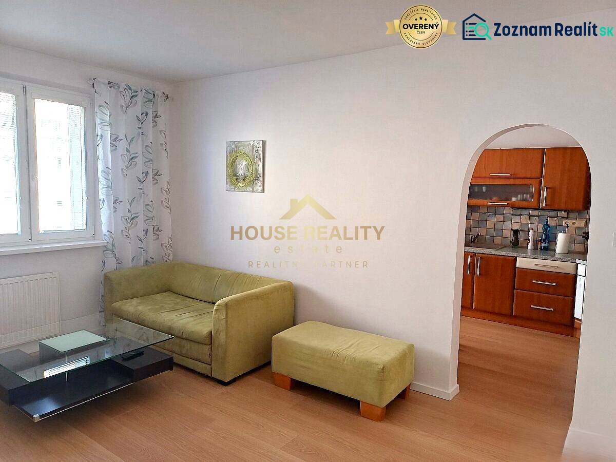 Living room in a 3-room apartment with a sofa, table, and kitchenette.