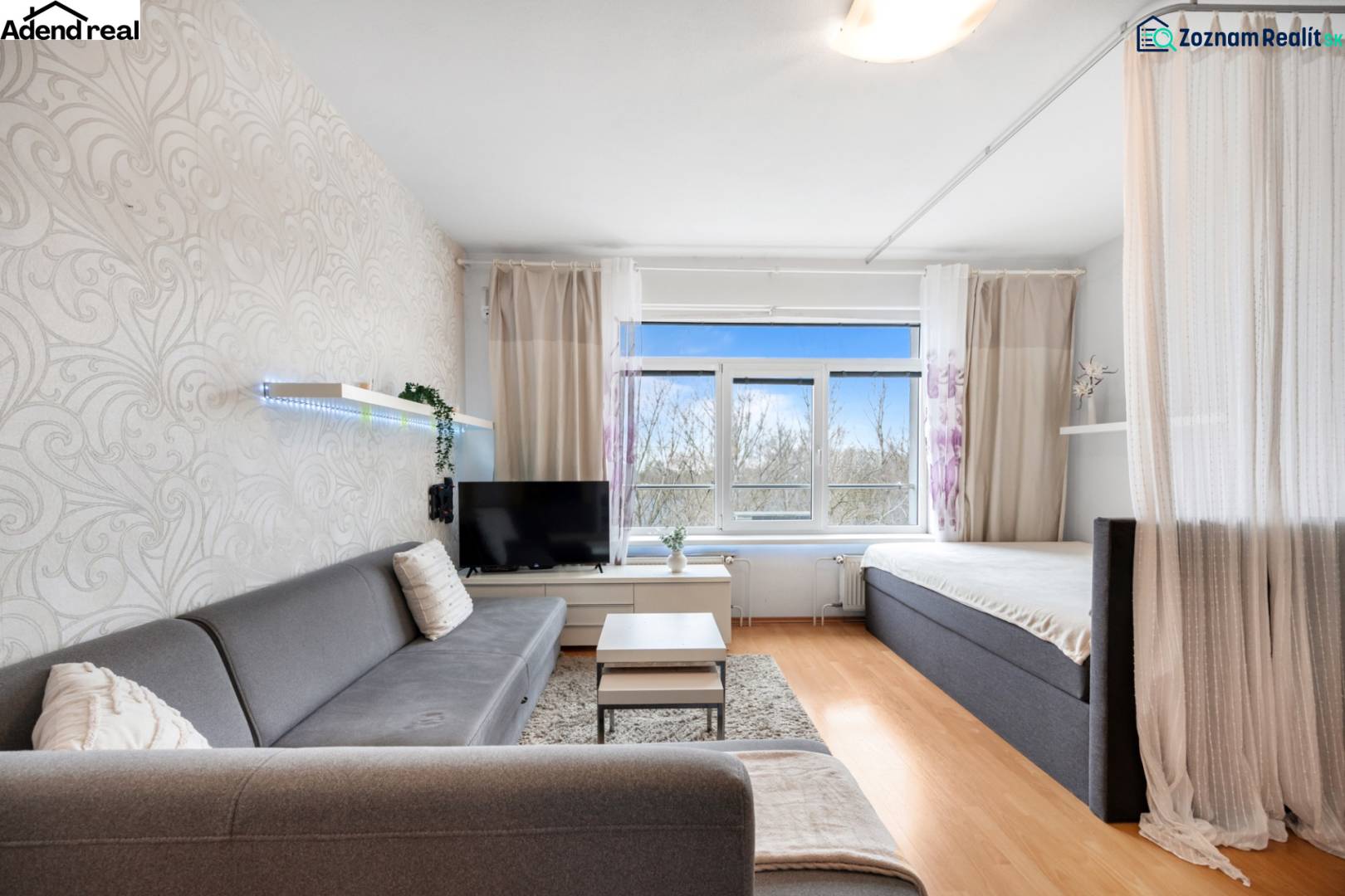 Living room with a sofa, curtain, and television, floor with wooden decor.