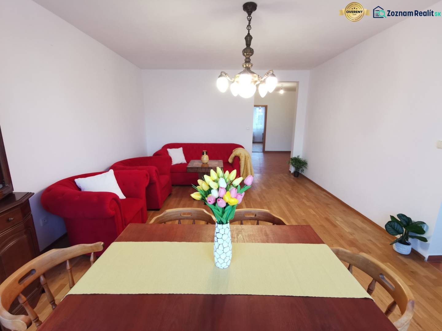 4-room apartment with red seating, dining table, and floor with wood decor.