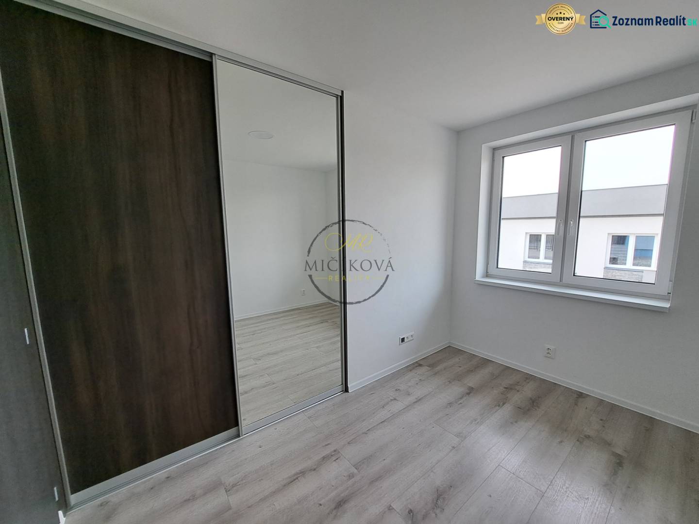 A room in a family house with a wooden decor floor and a large mirrored wardrobe.