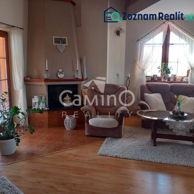 A comfortable living room in a family house with a fireplace, large windows, and soft sofas.